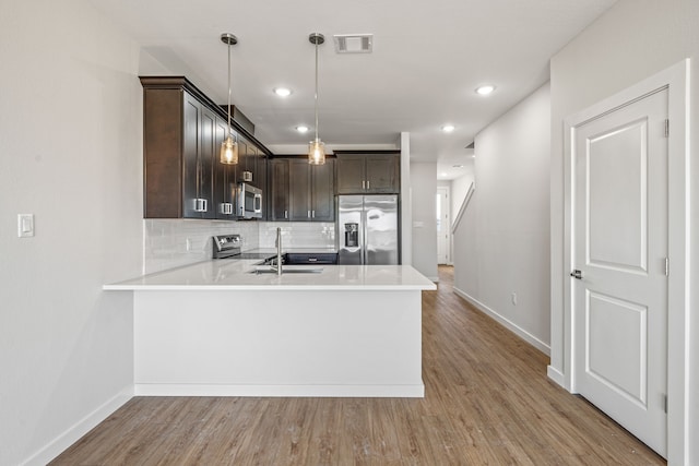 kitchen with light countertops, a sink, visible vents, dark brown cabinets, and appliances with stainless steel finishes