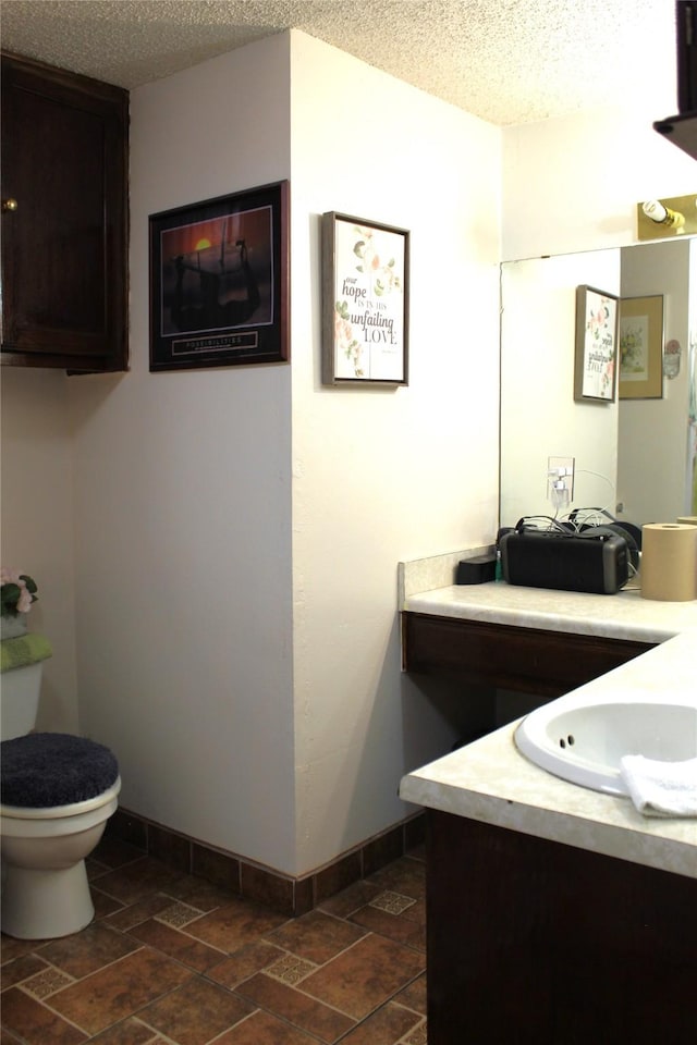1090 N Race St, Stephenville, TX 76401 - bathroom featuring toilet, vanity, baseboards, and a textured ceiling