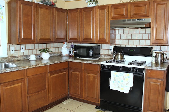 1090 N Race St, Stephenville, TX 76401 - kitchen featuring under cabinet range hood, black microwave, gas stove, and brown cabinets