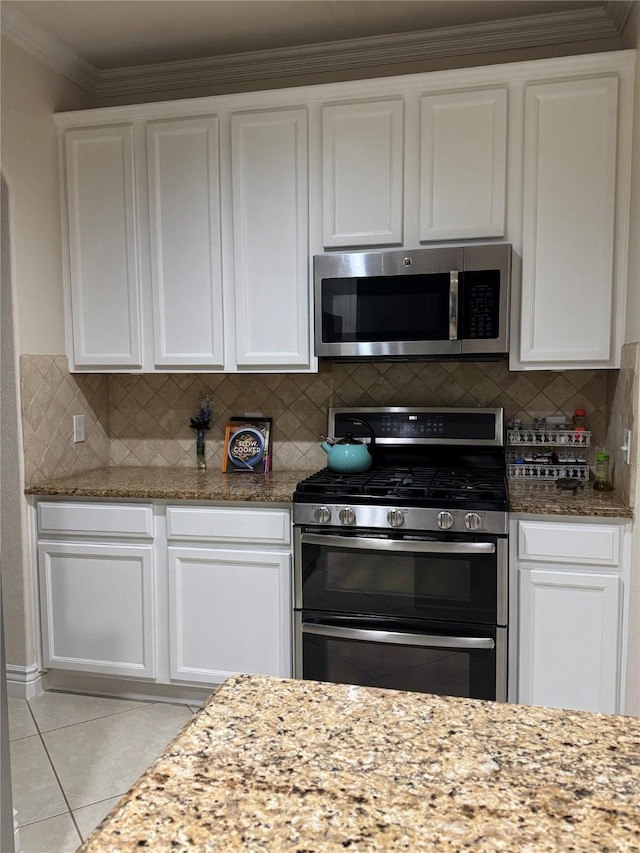 1431 Bonham Pkwy, Lantana, TX 76226 - kitchen featuring appliances with stainless steel finishes, white cabinetry, light stone counters, backsplash, and crown molding