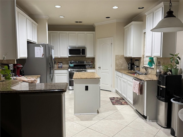 1431 Bonham Pkwy, Lantana, TX 76226 - kitchen featuring appliances with stainless steel finishes, a center island, light tile patterned flooring, crown molding, and backsplash