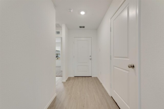 hallway with baseboards, visible vents, and light wood-style flooring