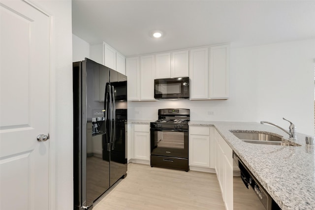 kitchen featuring a sink, light wood-style flooring, white cabinets, and black appliances