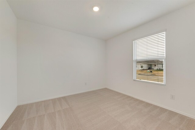 spare room with baseboards, recessed lighting, and light colored carpet