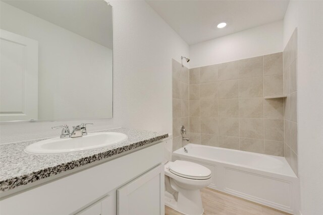bathroom with toilet, vanity, wood finished floors, tub / shower combination, and recessed lighting