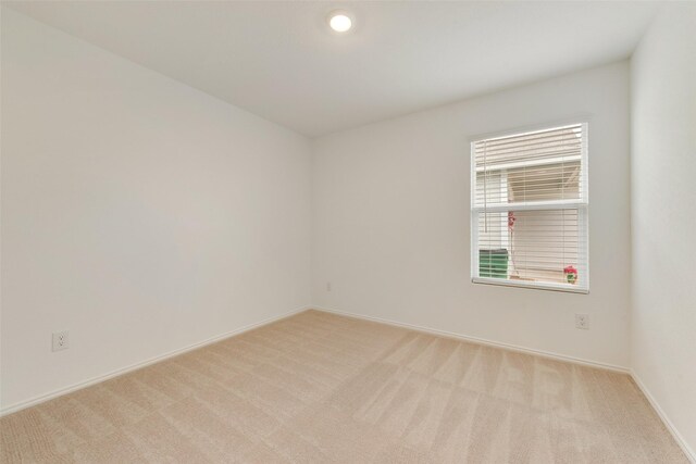 empty room featuring baseboards and light colored carpet