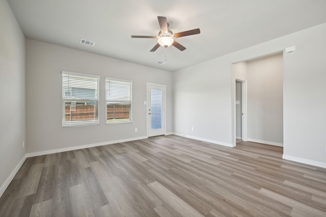 empty room with a ceiling fan, wood finished floors, baseboards, and visible vents