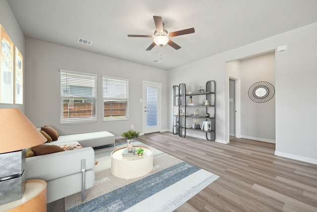 living area with baseboards, visible vents, a ceiling fan, and wood finished floors