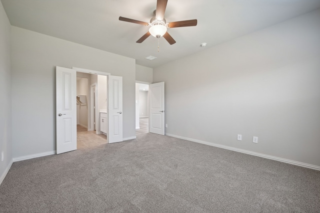 unfurnished bedroom featuring baseboards, ensuite bath, ceiling fan, and light carpet