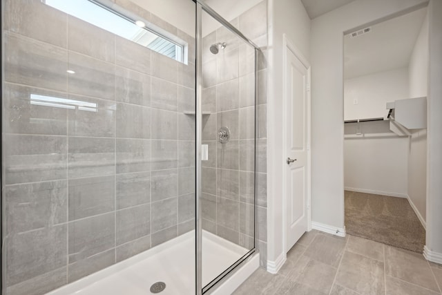full bathroom featuring visible vents, a walk in closet, baseboards, and a shower stall