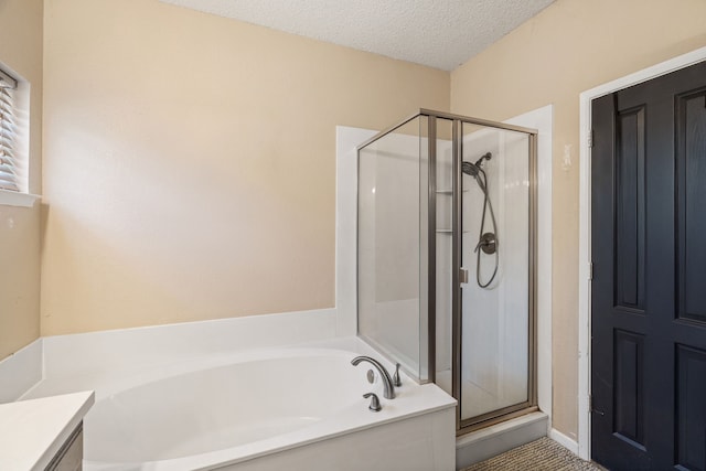 bathroom featuring a shower stall, a textured ceiling, vanity, and a garden tub