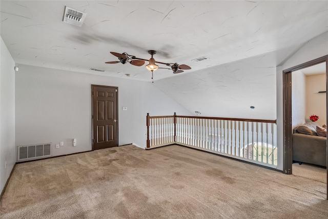 empty room with visible vents, vaulted ceiling, and a ceiling fan