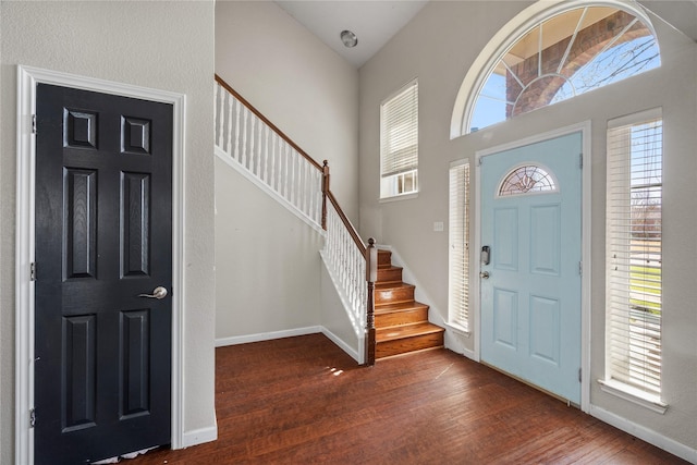 foyer entrance with a high ceiling, baseboards, stairway, and wood finished floors