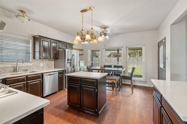 kitchen featuring a sink, backsplash, dishwasher, a center island, and dark wood-type flooring