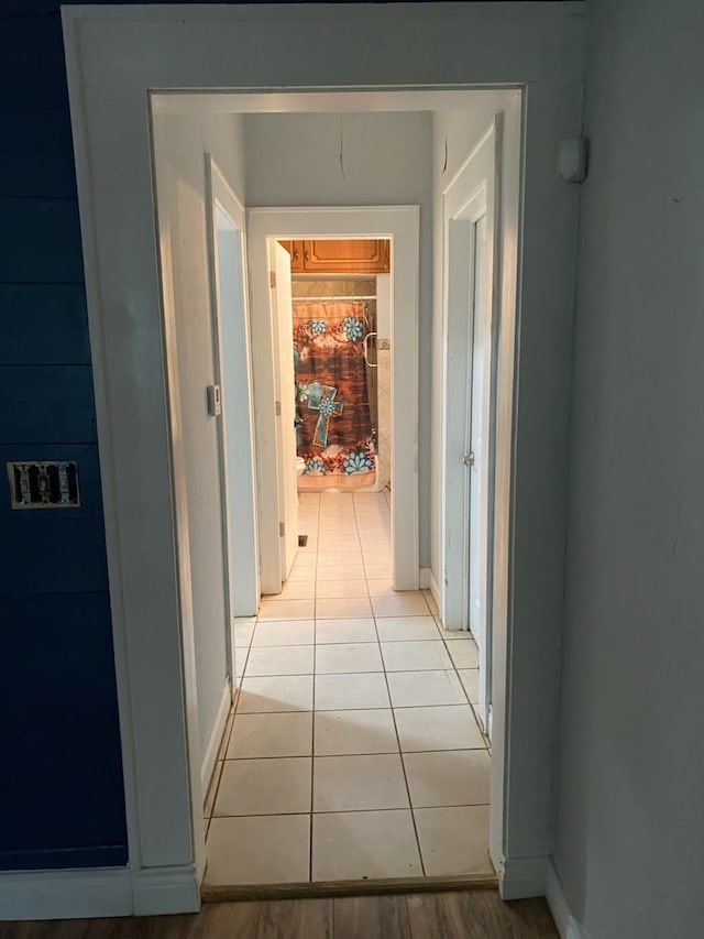 hall featuring light tile patterned flooring and baseboards