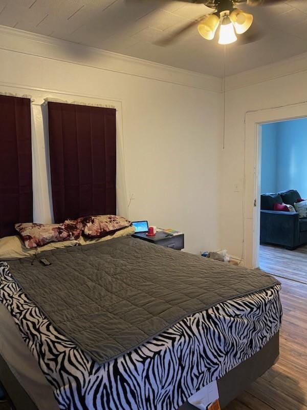 bedroom featuring crown molding, wood finished floors, and ceiling fan