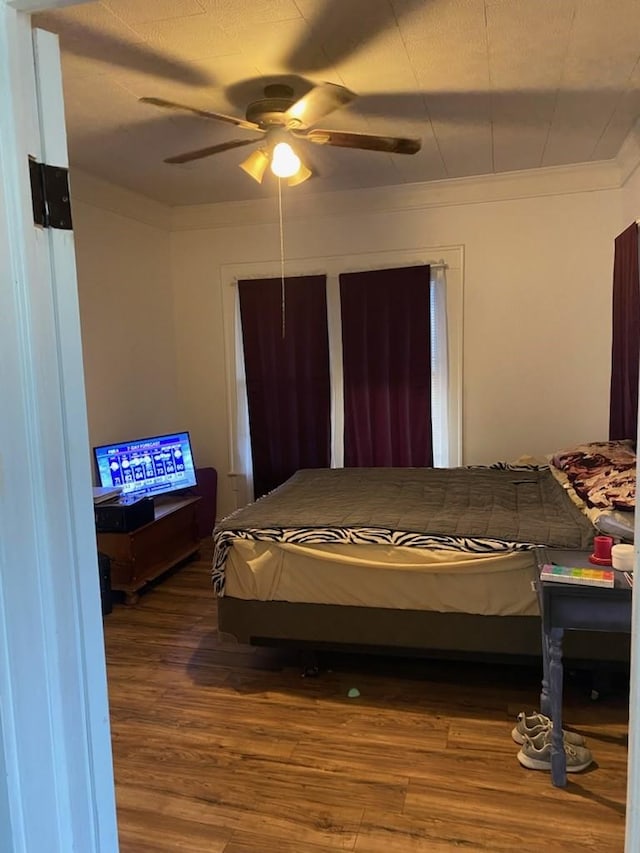 bedroom with crown molding, wood finished floors, and a ceiling fan