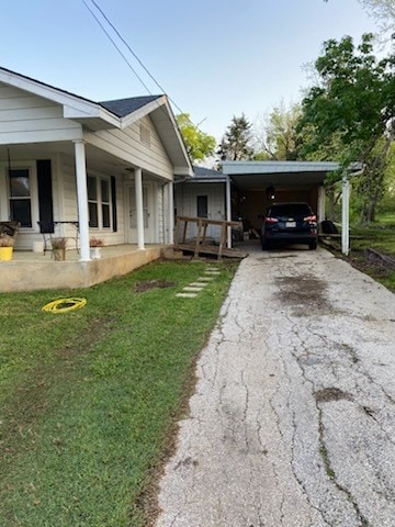 view of side of property with driveway, a porch, a yard, and a carport