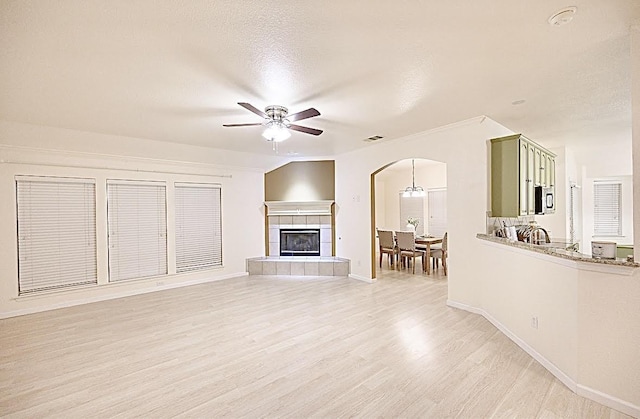 8729 Shavano Dr, Fort Worth, TX 76123 - unfurnished living room featuring arched walkways, ceiling fan, light wood-type flooring, and baseboards