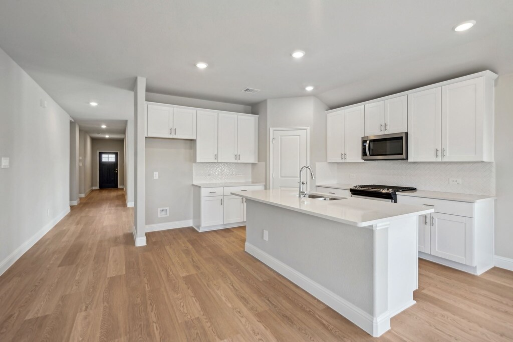 603 Weller Rd, Lowry Crossing, TX 75069 - kitchen featuring white cabinets, a sink, appliances with stainless steel finishes, and light wood finished floors