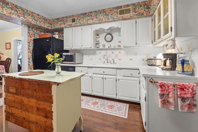 kitchen featuring stainless steel microwave, ornamental molding, dark wood-style floors, freestanding refrigerator, and a sink