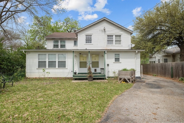 view of front facade featuring french doors, aphalt driveway, a front yard, and fence