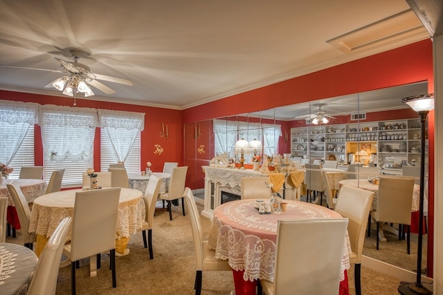 carpeted dining space featuring visible vents, a ceiling fan, and crown molding