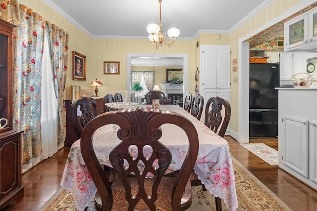 dining area with crown molding, a chandelier, and wood finished floors