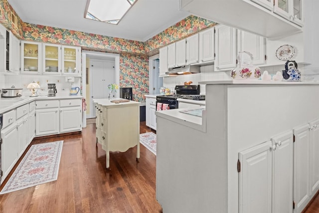 kitchen featuring light countertops, dark wood-style floors, under cabinet range hood, white cabinetry, and wallpapered walls