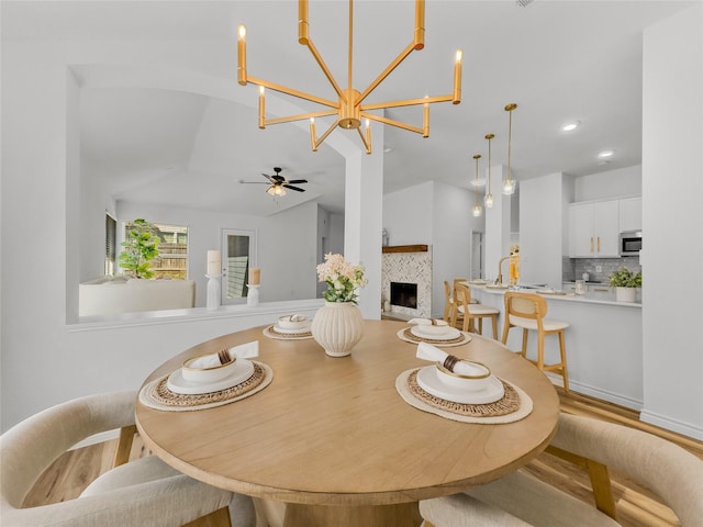 4512 Stepping Stone Dr, Fort Worth, TX 76123 - dining area with a tiled fireplace, ceiling fan with notable chandelier, lofted ceiling, and wood finished floors
