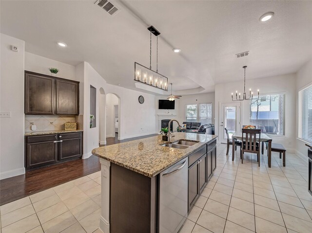 kitchen featuring visible vents, dishwasher, dark brown cabinets, arched walkways, and open floor plan