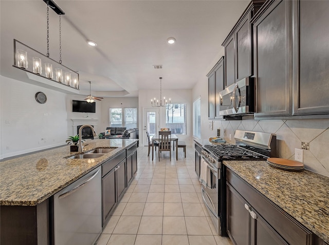 kitchen featuring light tile patterned flooring, stainless steel appliances, a sink, ceiling fan with notable chandelier, and open floor plan