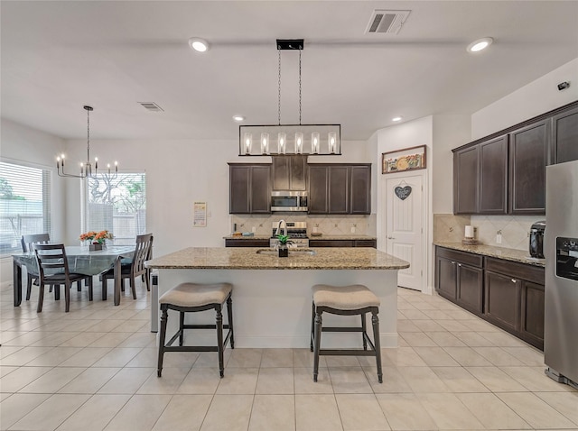 kitchen featuring a breakfast bar area, visible vents, stainless steel appliances, and a notable chandelier