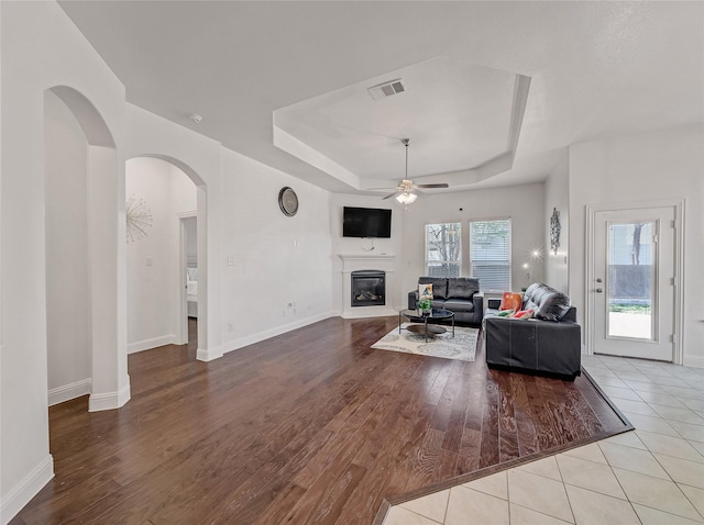 living room featuring visible vents, wood finished floors, a ceiling fan, and a raised ceiling