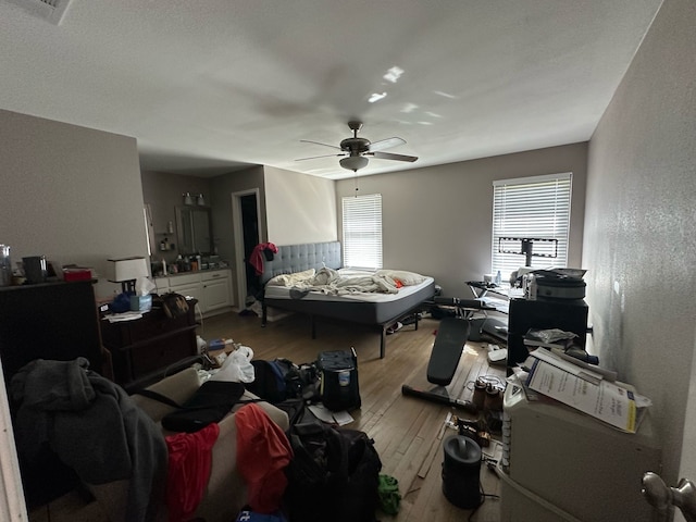 bedroom with visible vents, a textured wall, hardwood / wood-style flooring, and a ceiling fan