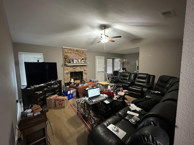 living room with lofted ceiling, visible vents, a ceiling fan, a fireplace, and wood finished floors