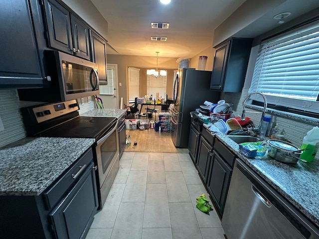 kitchen with a sink, a chandelier, backsplash, and appliances with stainless steel finishes