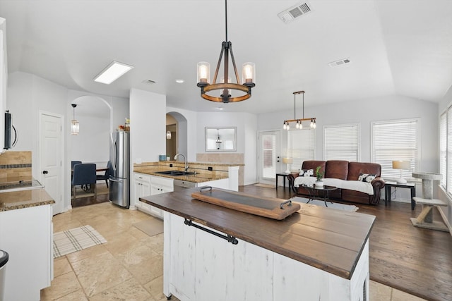 3505 Mustang Dr, Denton, TX 76210 - kitchen featuring arched walkways, appliances with stainless steel finishes, a sink, white cabinets, and plenty of natural light