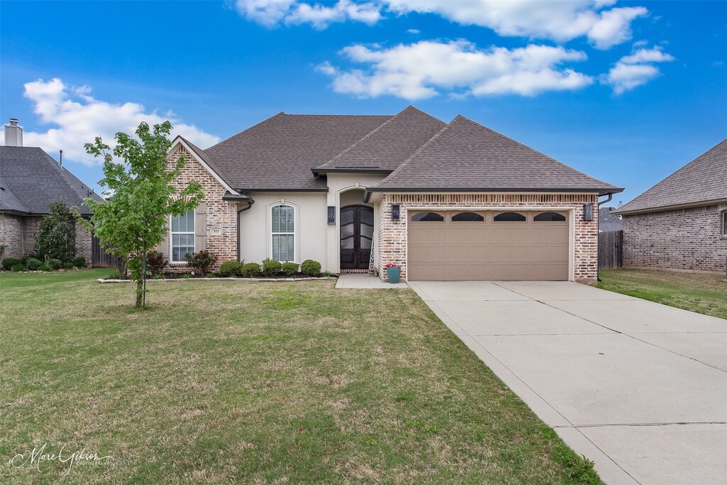 811 Durango Dr, Bossier City, LA 71111 - french country inspired facade with a front yard, concrete driveway, stucco siding, a shingled roof, and a garage