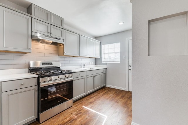 1312 Greenwood Dr, Garland, TX 75041 - kitchen with decorative backsplash, stainless steel gas range, under cabinet range hood, a sink, and gray cabinets
