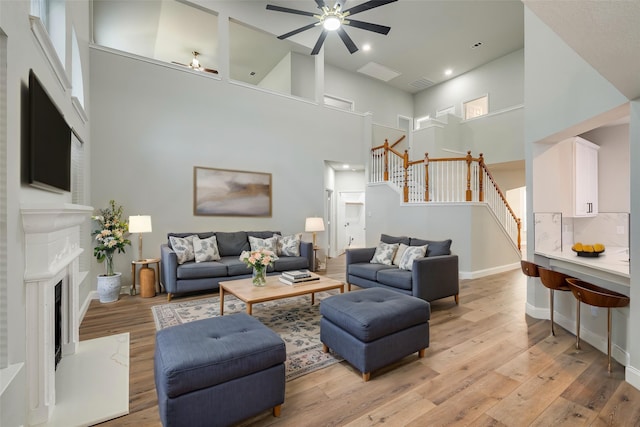 10 Monticello Ct, Mansfield, TX 76063 - living room featuring a towering ceiling, stairway, ceiling fan, light wood-style flooring, and a high end fireplace