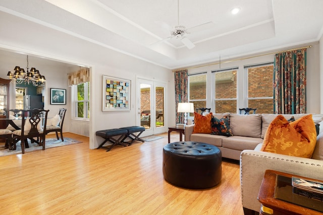 241 Tanbark Cir, Coppell, TX 75019 - living area with a tray ceiling, light wood-style flooring, a chandelier, ceiling fan, and crown molding