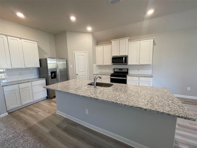 2100 Yarbrough, Anna, TX 75409 - kitchen featuring a sink, wood finished floors, a center island with sink, stainless steel appliances, and white cabinets