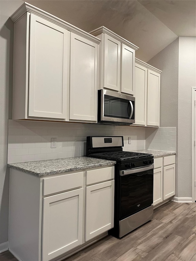 2100 Yarbrough, Anna, TX 75409 - kitchen featuring white cabinetry, light wood-type flooring, baseboards, decorative backsplash, and appliances with stainless steel finishes