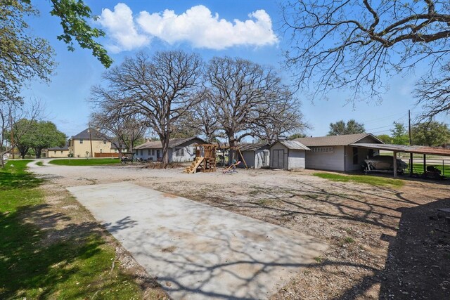 1509 Tinker Rd, Colleyville, TX 76034 - exterior space with driveway, an outdoor structure, a storage shed, a carport, and a playground