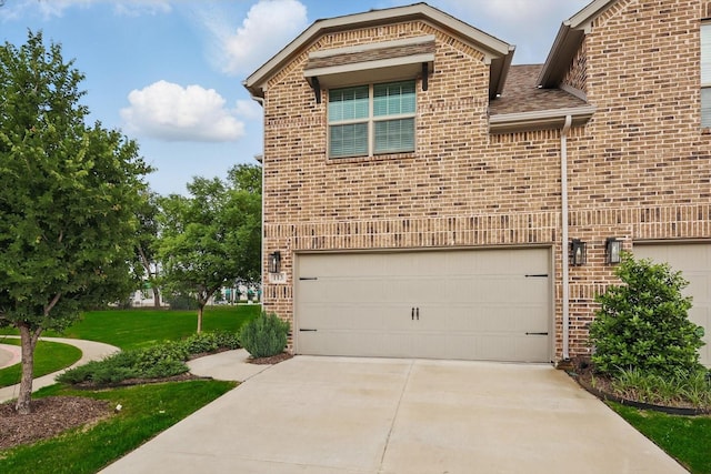 view of home's exterior with brick siding, concrete driveway, a garage, a yard, and roof with shingles