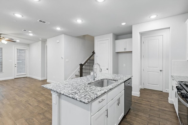 kitchen with a sink, gas stove, dark wood-style flooring, white cabinetry, and ceiling fan