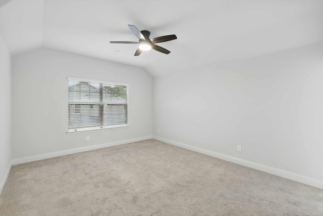 empty room featuring lofted ceiling, a ceiling fan, baseboards, and carpet flooring