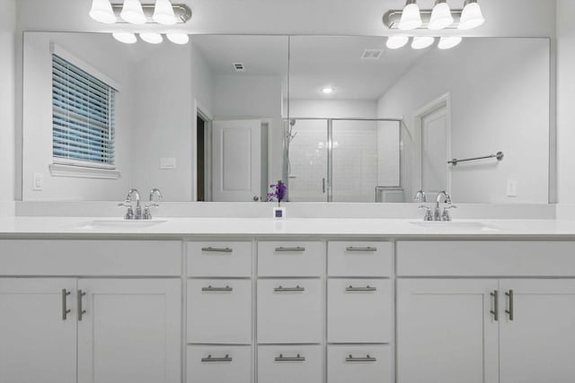 bathroom with a shower stall and double vanity