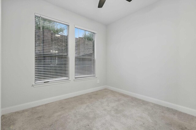 carpeted empty room with ceiling fan and baseboards